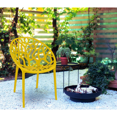 ogród z wykorzystaniem nowoczesnego żółtego krzesła ażurowego Moso